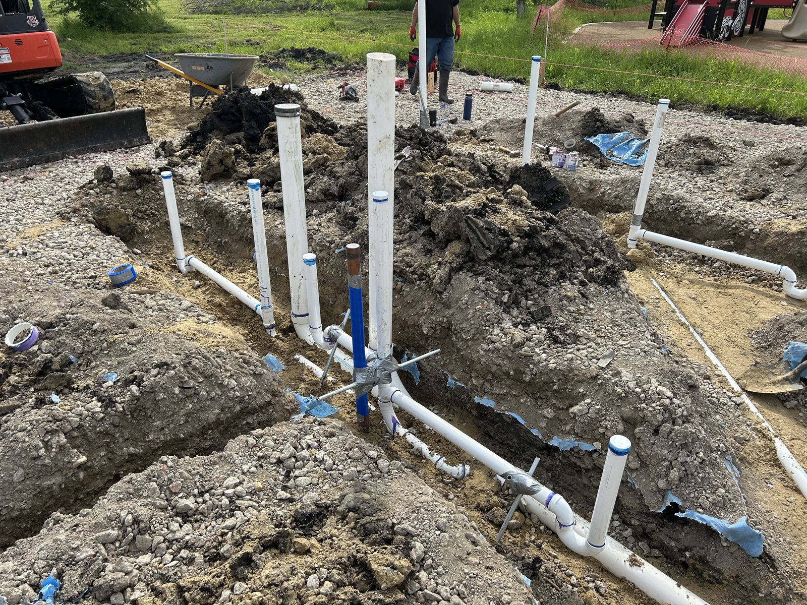 Commercial underground drain-waste-vent rough-in with PVC stub-ups set in trenches
