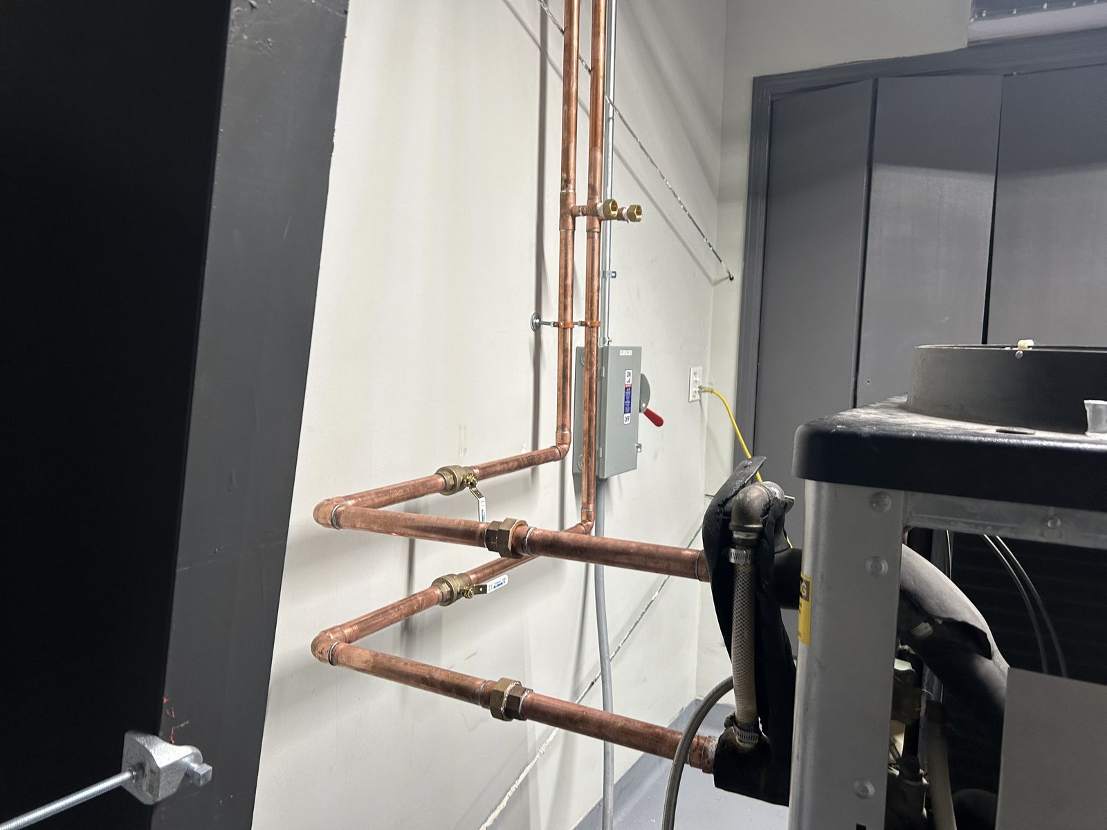 Clean copper mechanical piping run to a chiller unit with electrical disconnect indoors