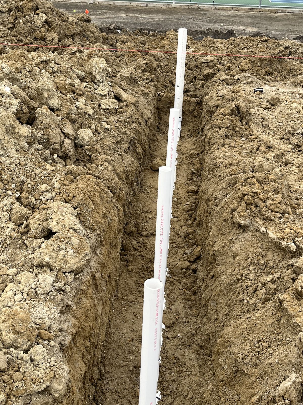 Deep excavated trench with a straight PVC sewer main run for a commercial site