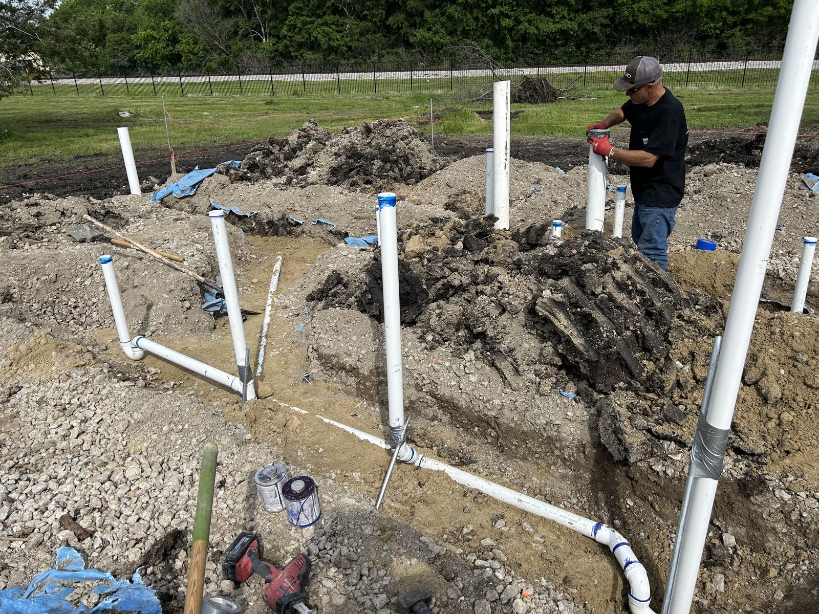 Sanitary drain-waste-vent rough-in with PVC stub-ups being installed on an outdoor jobsite
