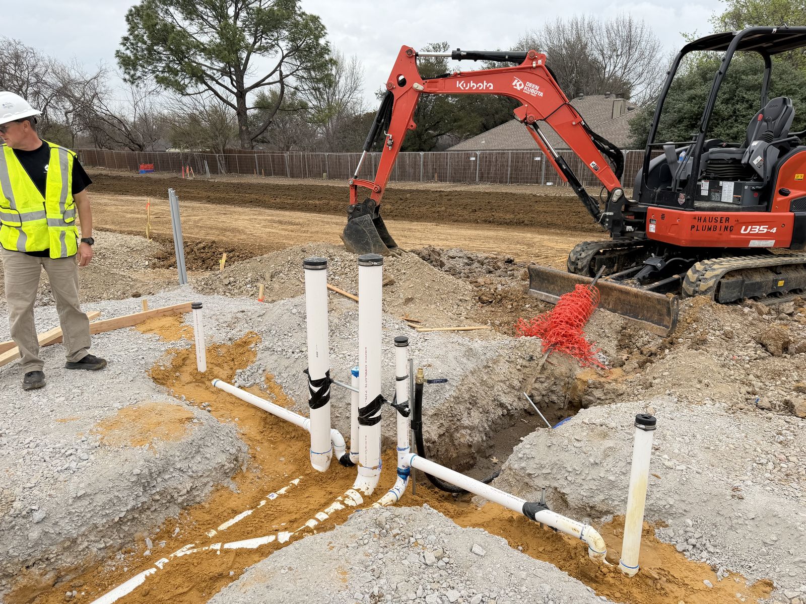 Hauser Plumbing branded Kubota excavator and underground plumbing rough-in on a DFW commercial jobsite